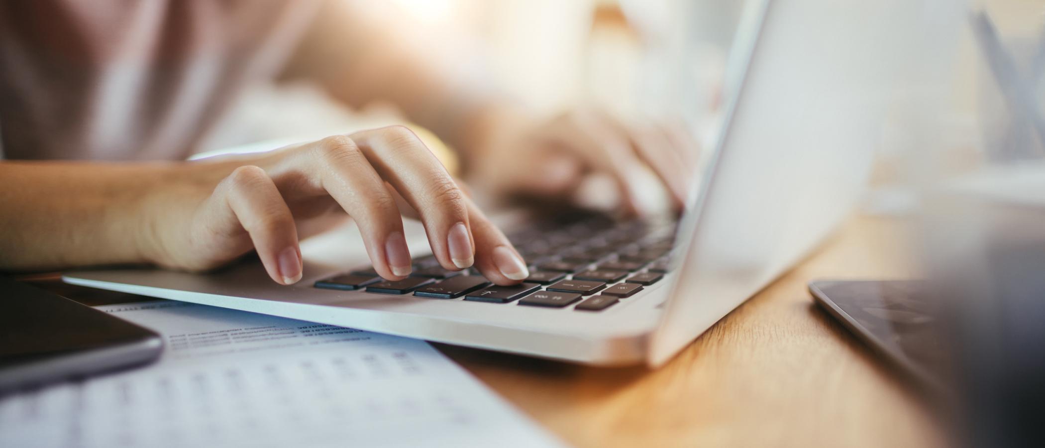 Eine Frauenhand auf der Tastatur eines Laptops