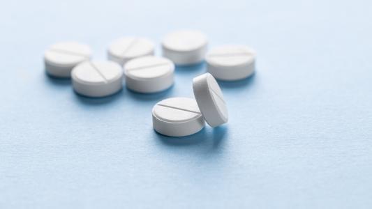 Acht weiße Tabletten liegen auf einer blauen Oberfläche