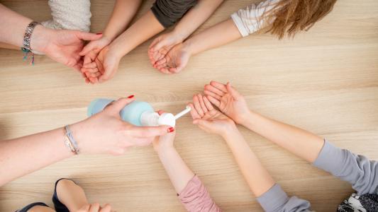 Ein Desinfektionsmittel wird auf viele Kinderhände verteilt
