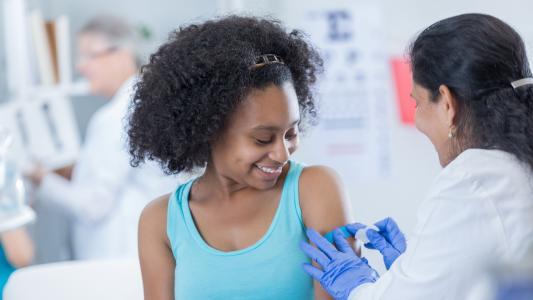 Junge Frau lässt sich von einer Ärztin impfen